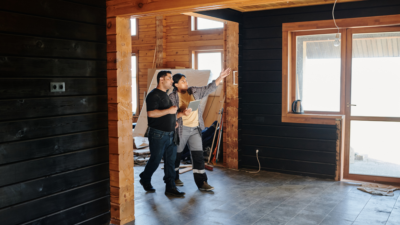 A man and a woman are standing in a room in a wooden house.