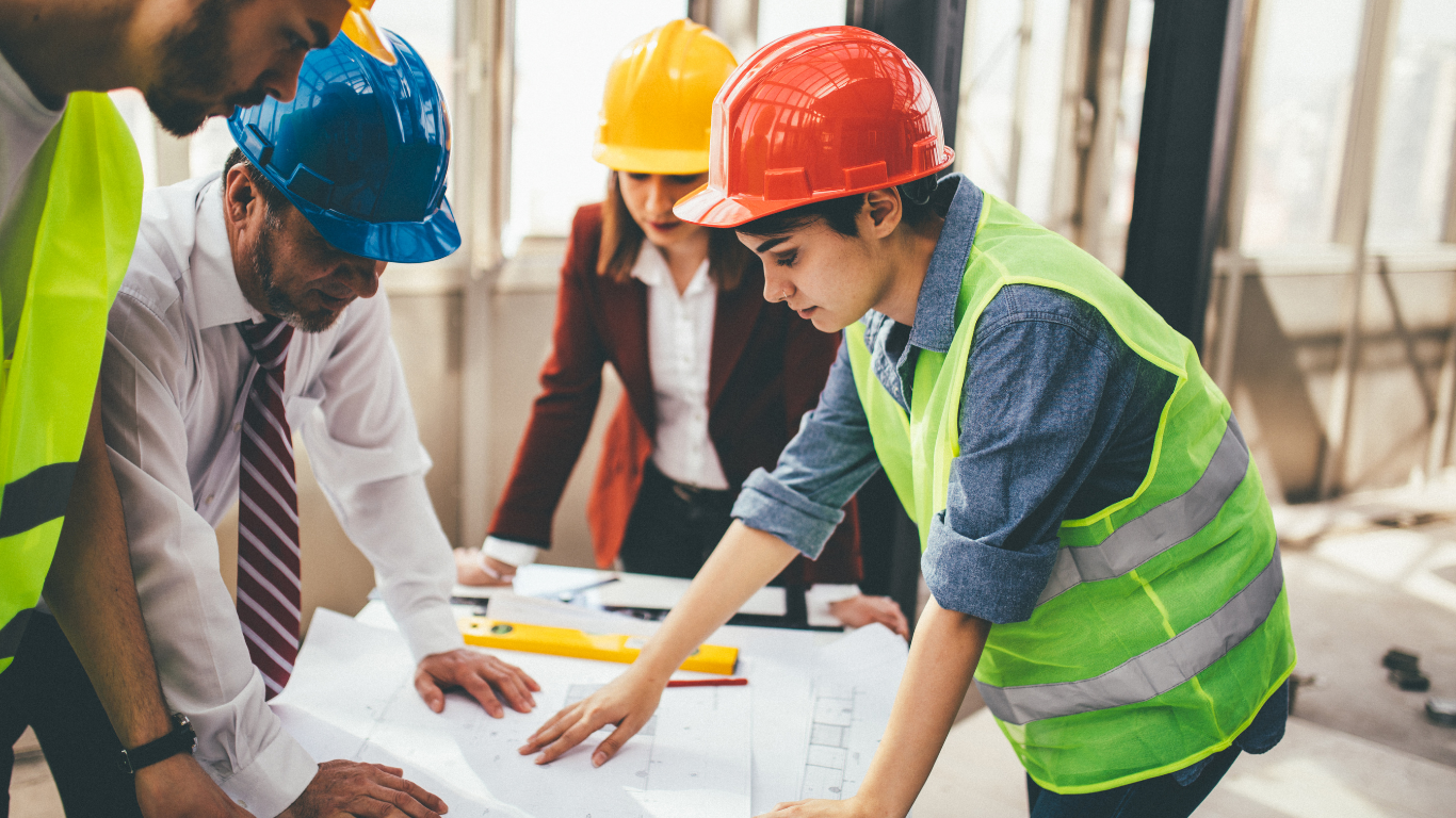 A group of construction workers are looking at a blueprint.