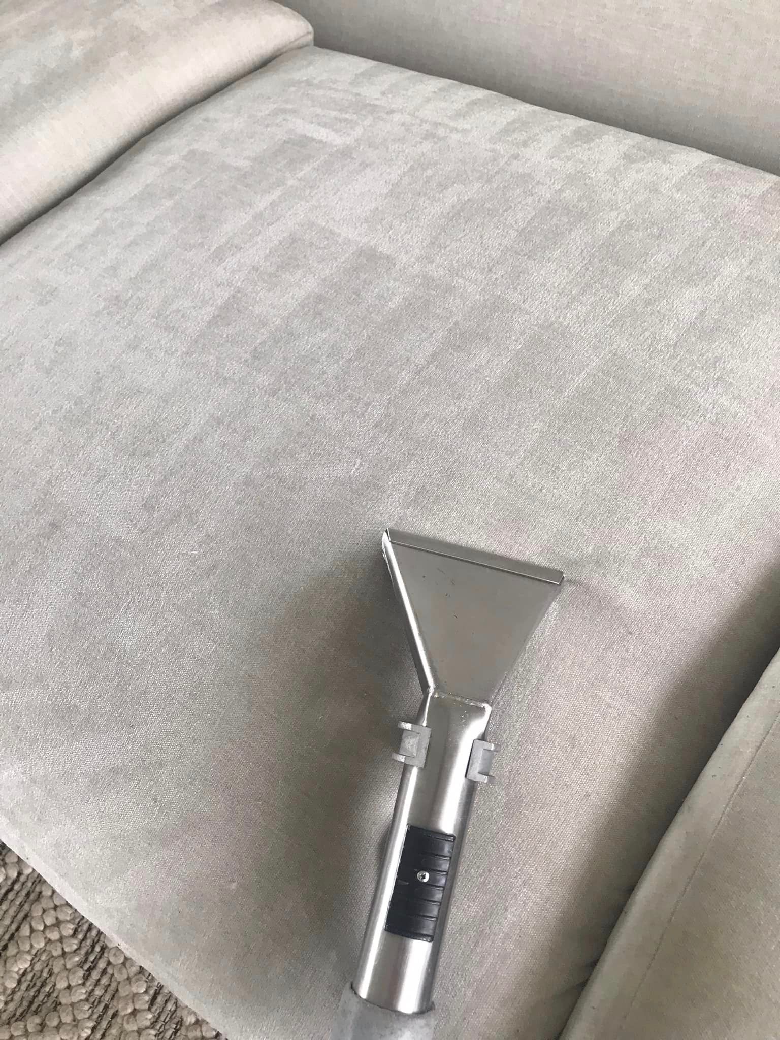 A vacuum cleaner is sitting on top of a couch.
