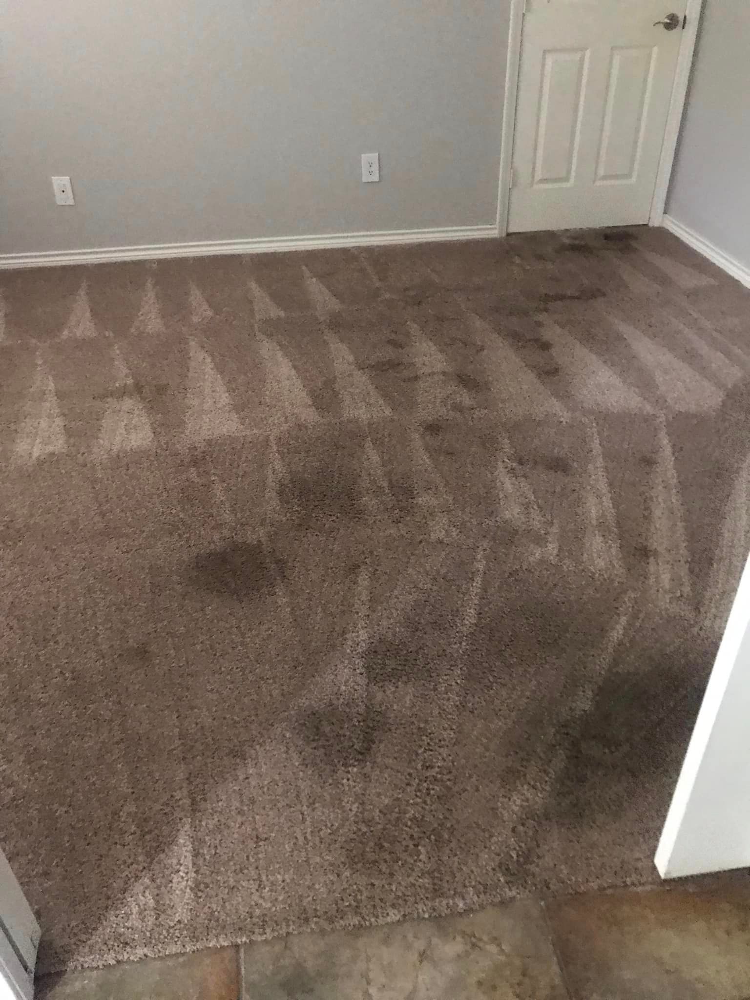A room with a dirty carpet and a door.
