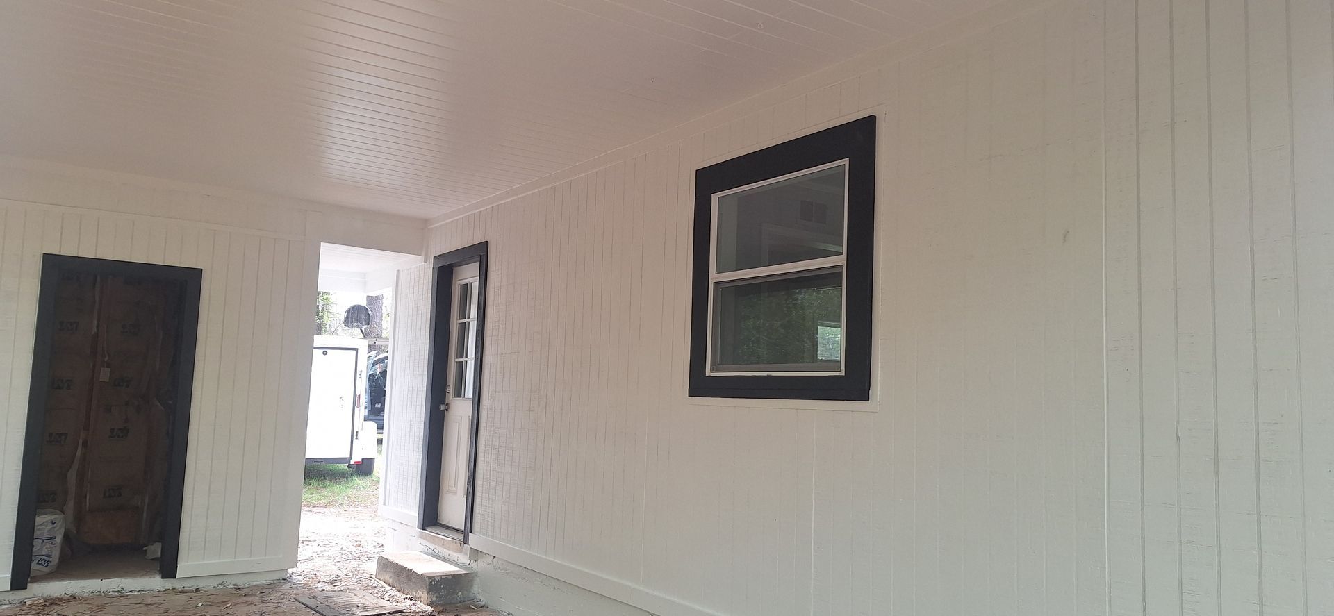 Empty white hallway with a door opening to the outside and a framed picture on the wall