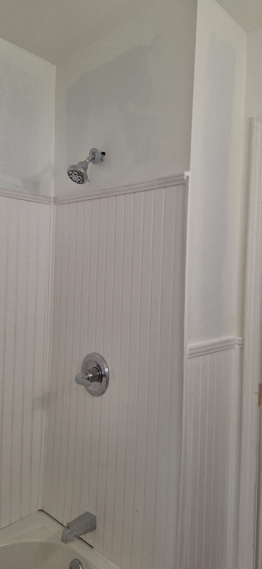 Bathroom shower with white beadboard walls and silver fixtures
