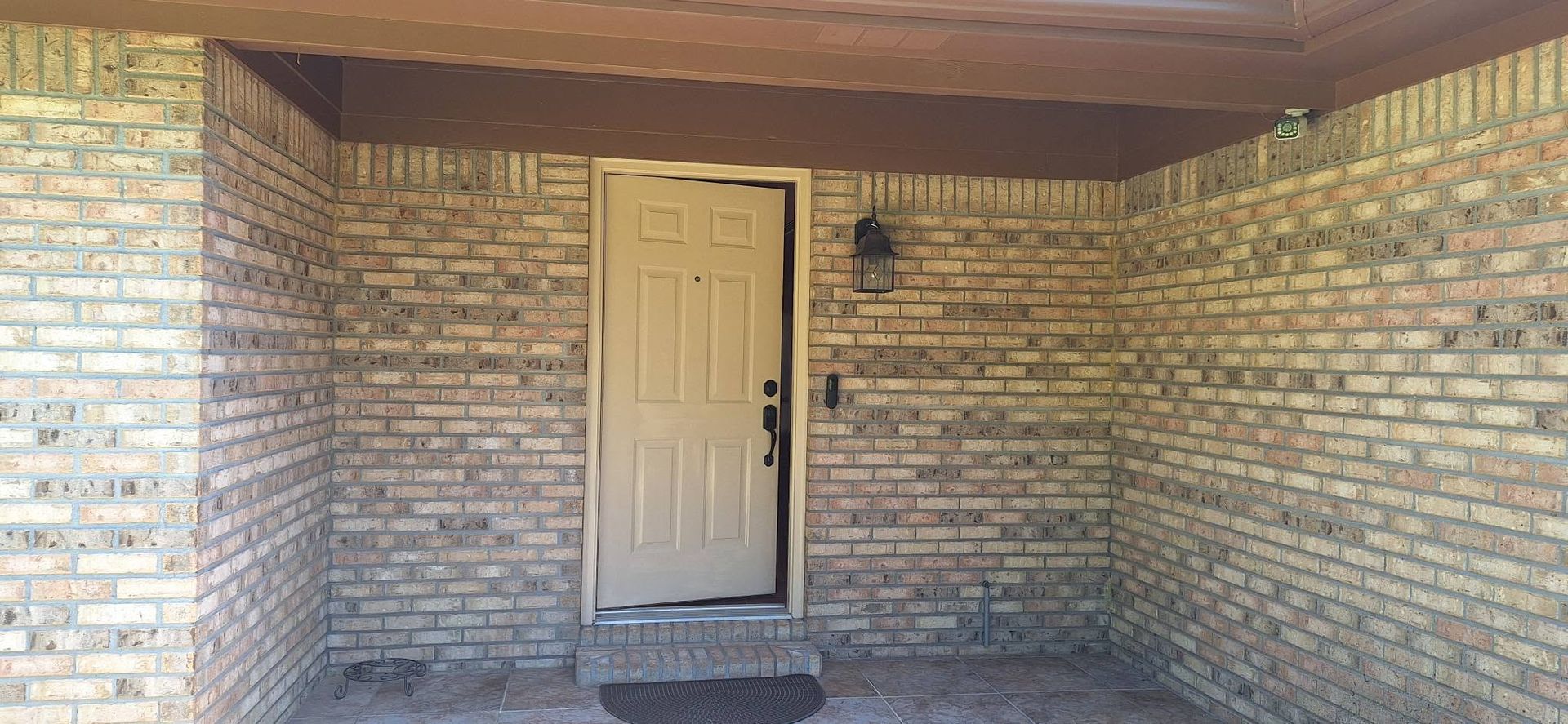 Brick house entryway with beige front door under a covered porch