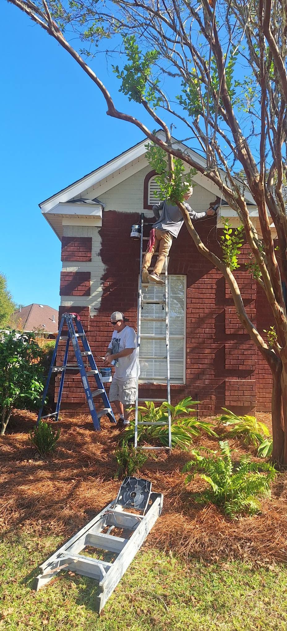 Red brick house with roof damage, a ladder, and a tree in the front yard