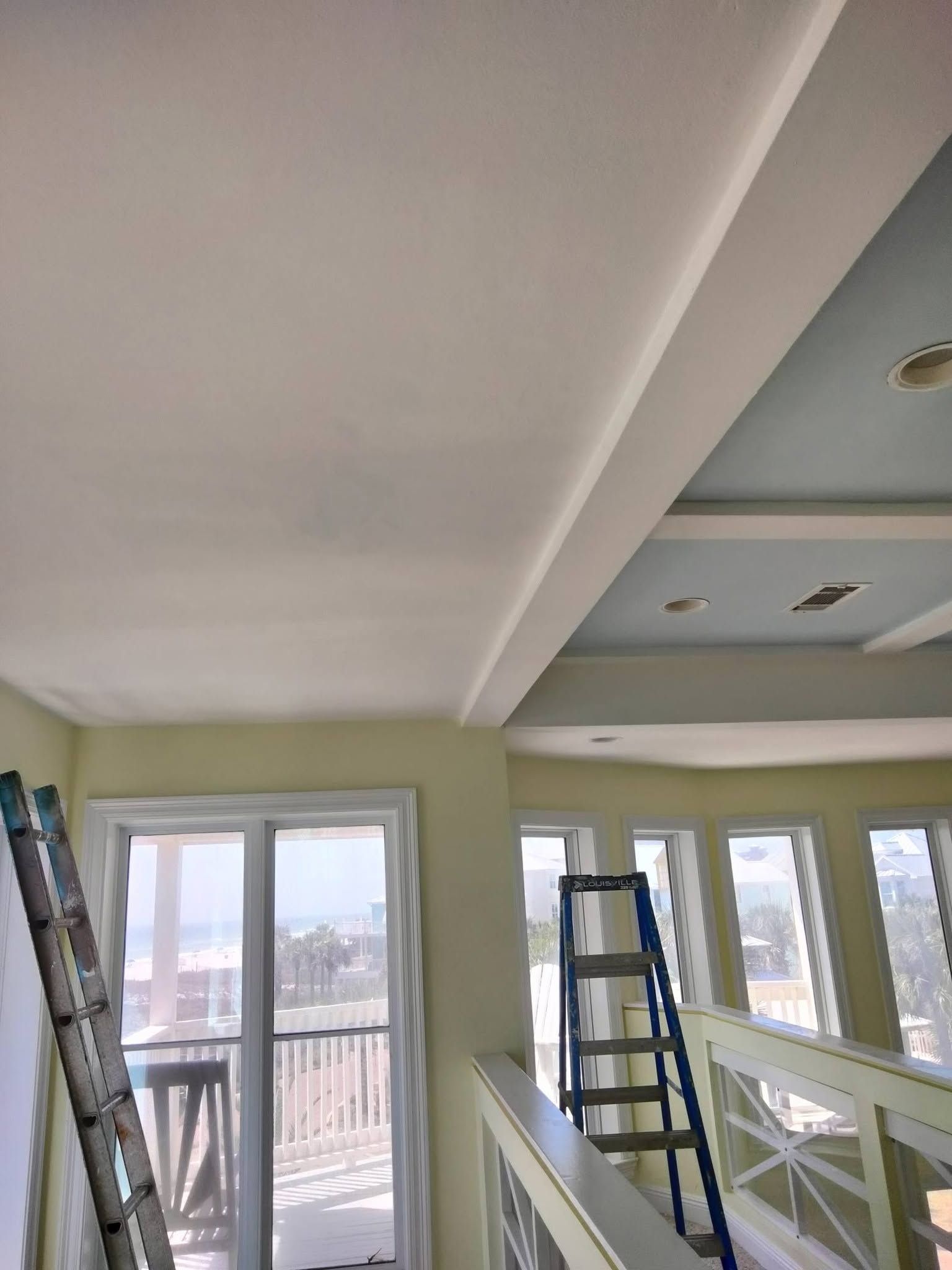 Bright room with white railings, ladders, and windows during interior renovation