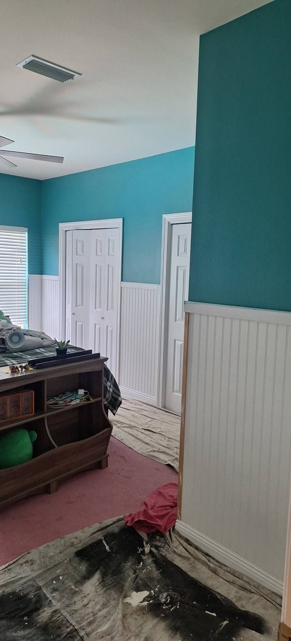 Partially renovated room with turquoise walls, white trim, and debris on the floor