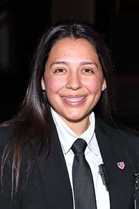 A woman in a suit and tie is smiling for the camera.