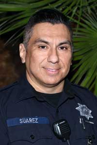A man in a police uniform is smiling and wearing a microphone.