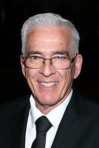 A man wearing glasses and a suit and tie is smiling.