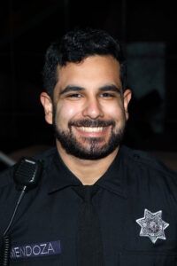 A man with a beard is wearing a police uniform and smiling.