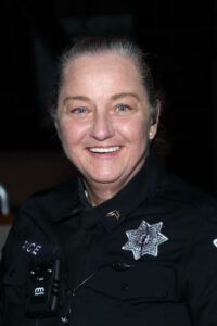 A woman in a police uniform is smiling for the camera.