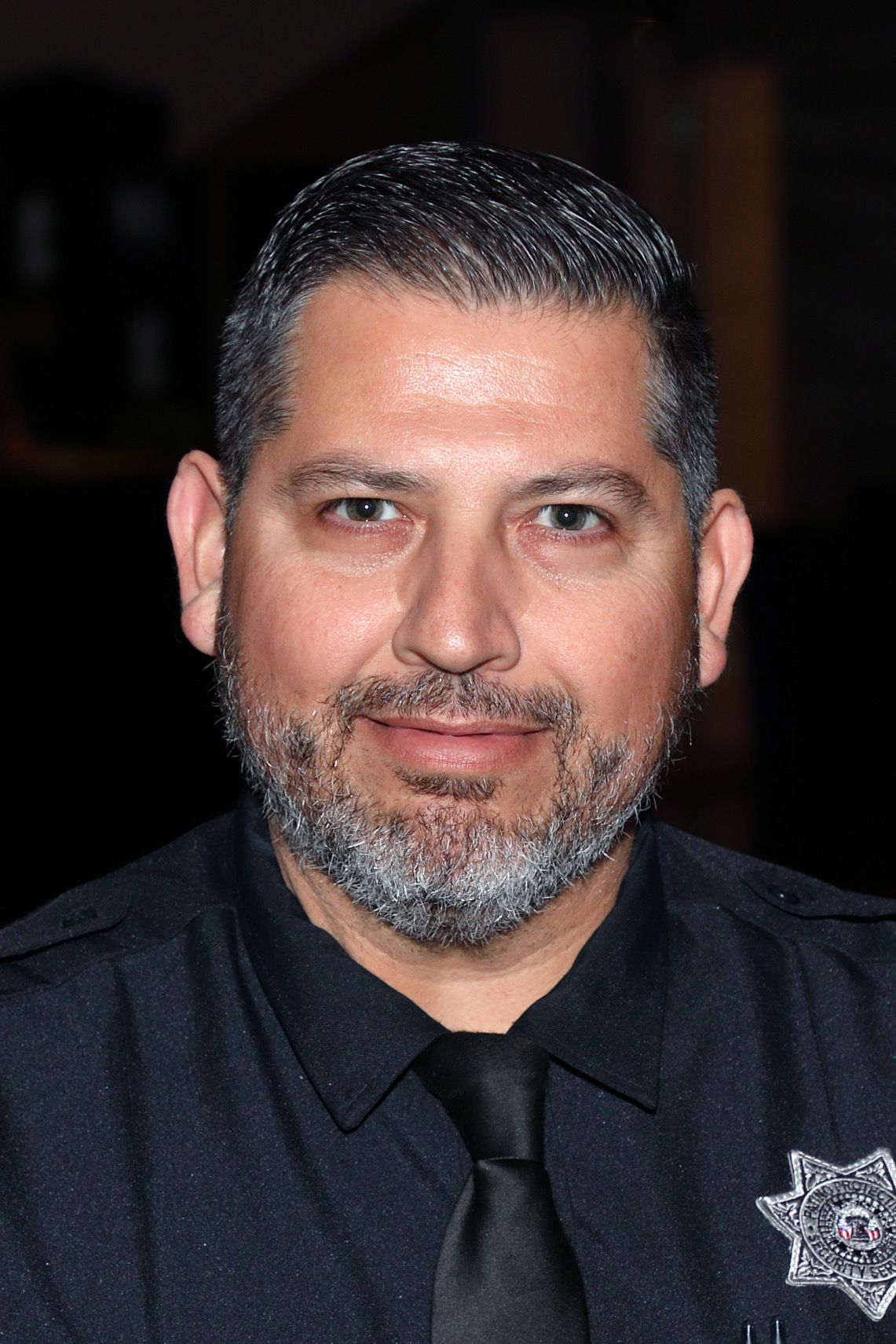 A man with a beard is wearing a police uniform and tie.