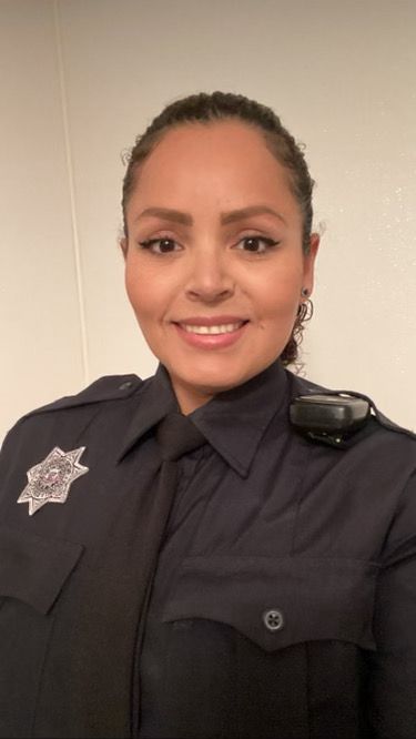 A woman in a police uniform is smiling for the camera.