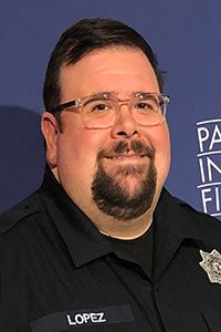 A man with a beard and glasses is wearing a police uniform.