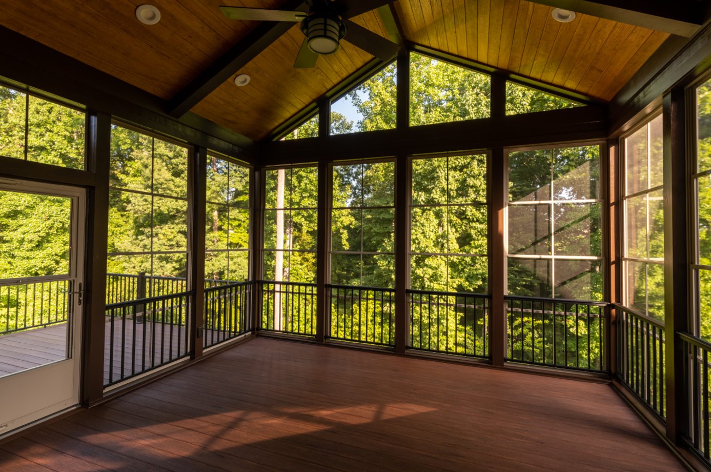 Wood-paneled screened porch with large windows overlooking a green forest.