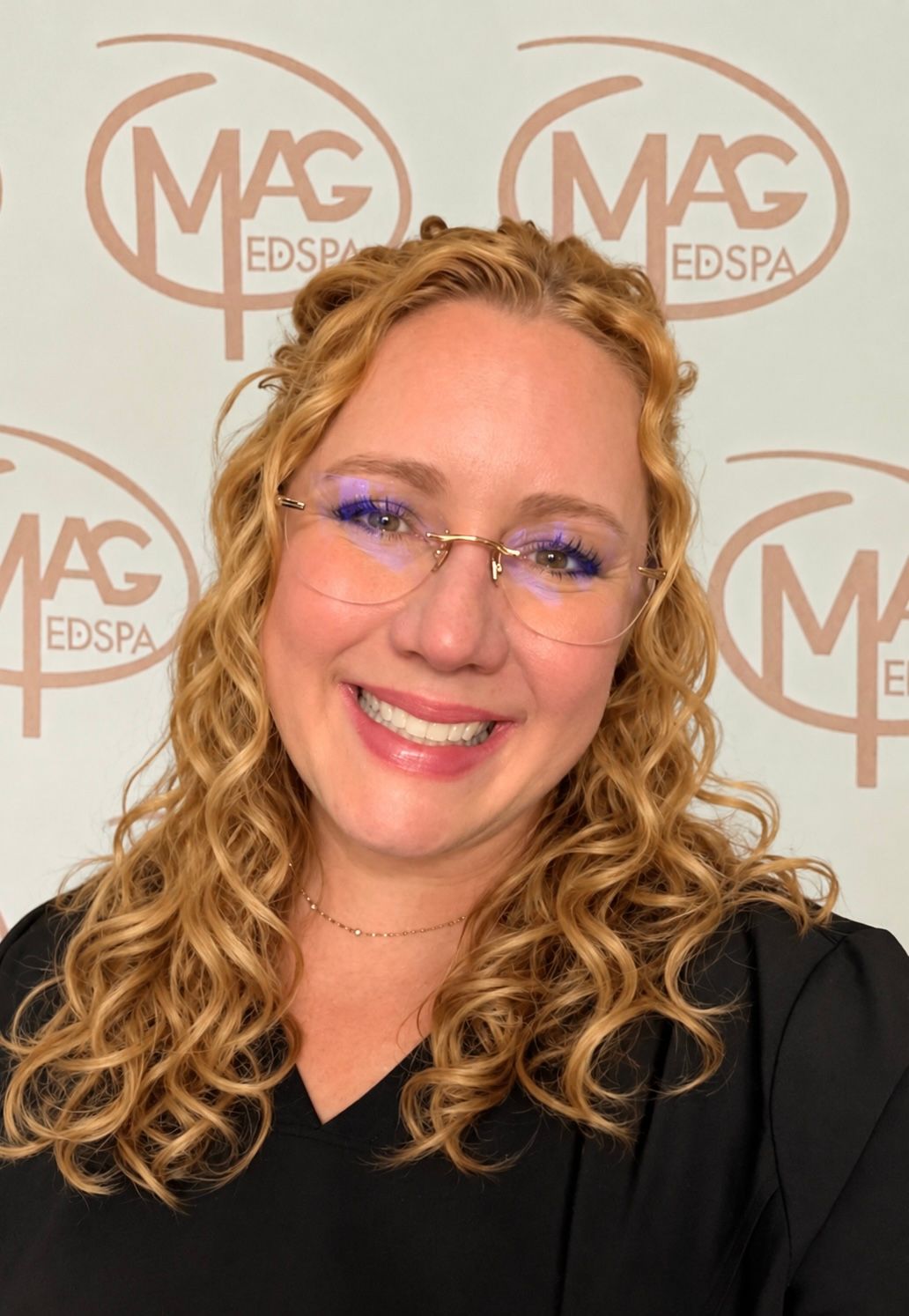 A woman wearing a necklace and hoop earrings smiles for the camera