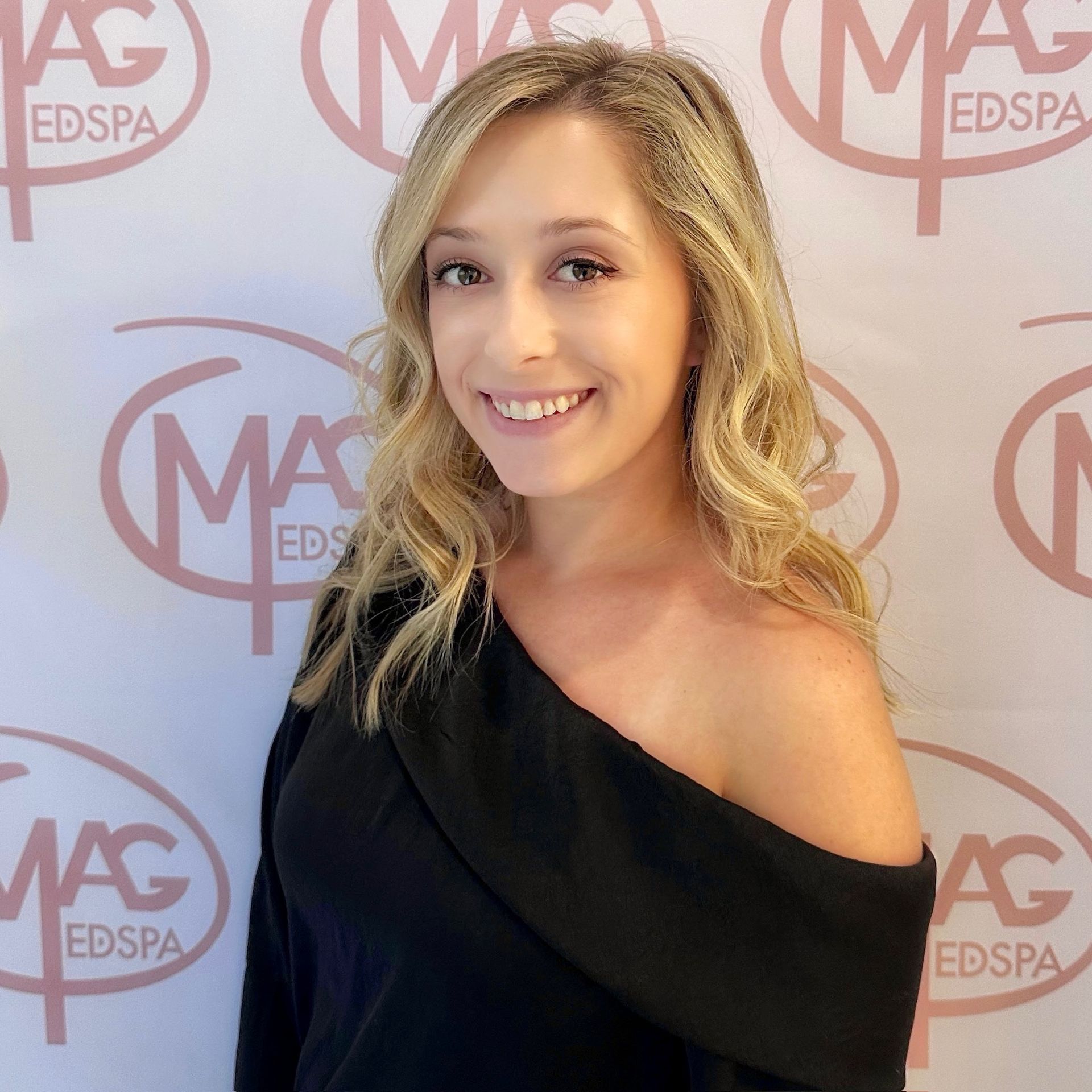 A woman wearing a necklace and hoop earrings smiles for the camera