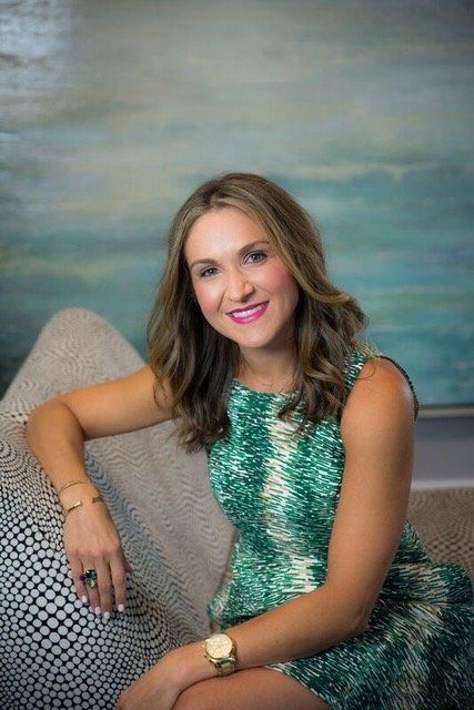 A woman in a green dress is sitting on a couch.