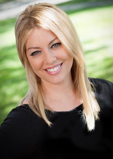 A woman with blonde hair is smiling and wearing a black shirt.