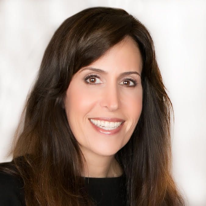 A woman with long brown hair is smiling for the camera