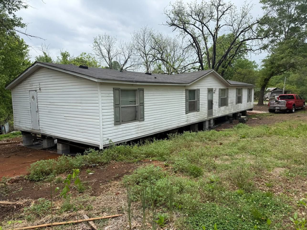 A mobile home is sitting in the middle of a grassy field.