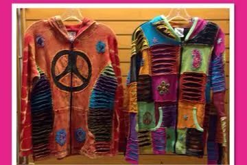 Two colorful patchwork coats hanging side by side, one with a peace symbol on the front.