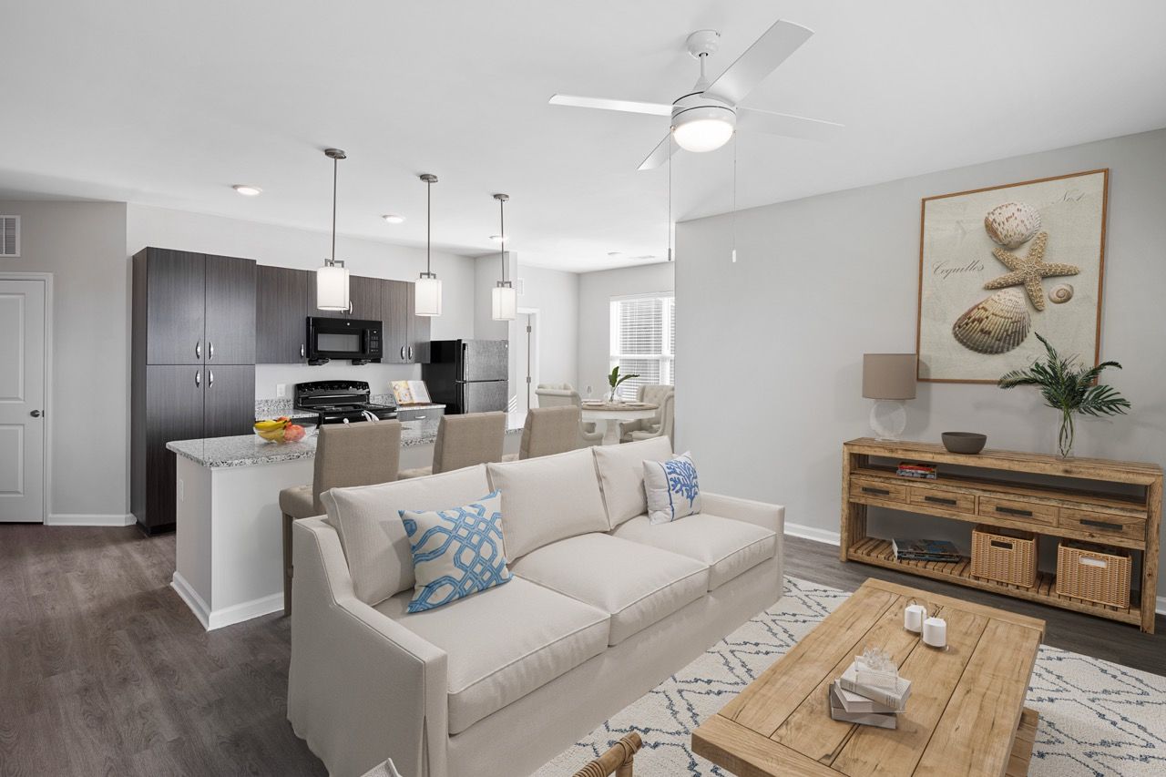 Open-concept apartment living area with a beige sofa, wooden coffee table, and a kitchen island.