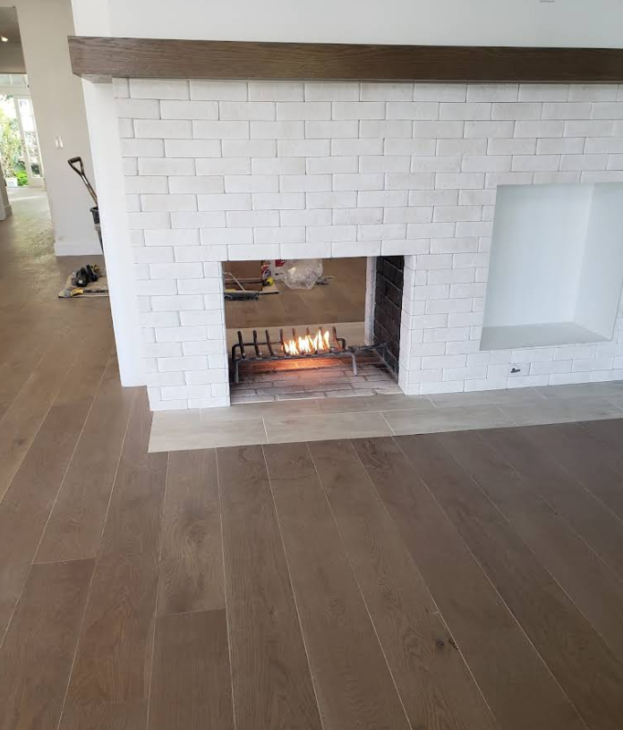 White brick fireplace with a small fire burning in a modern living room with wood flooring