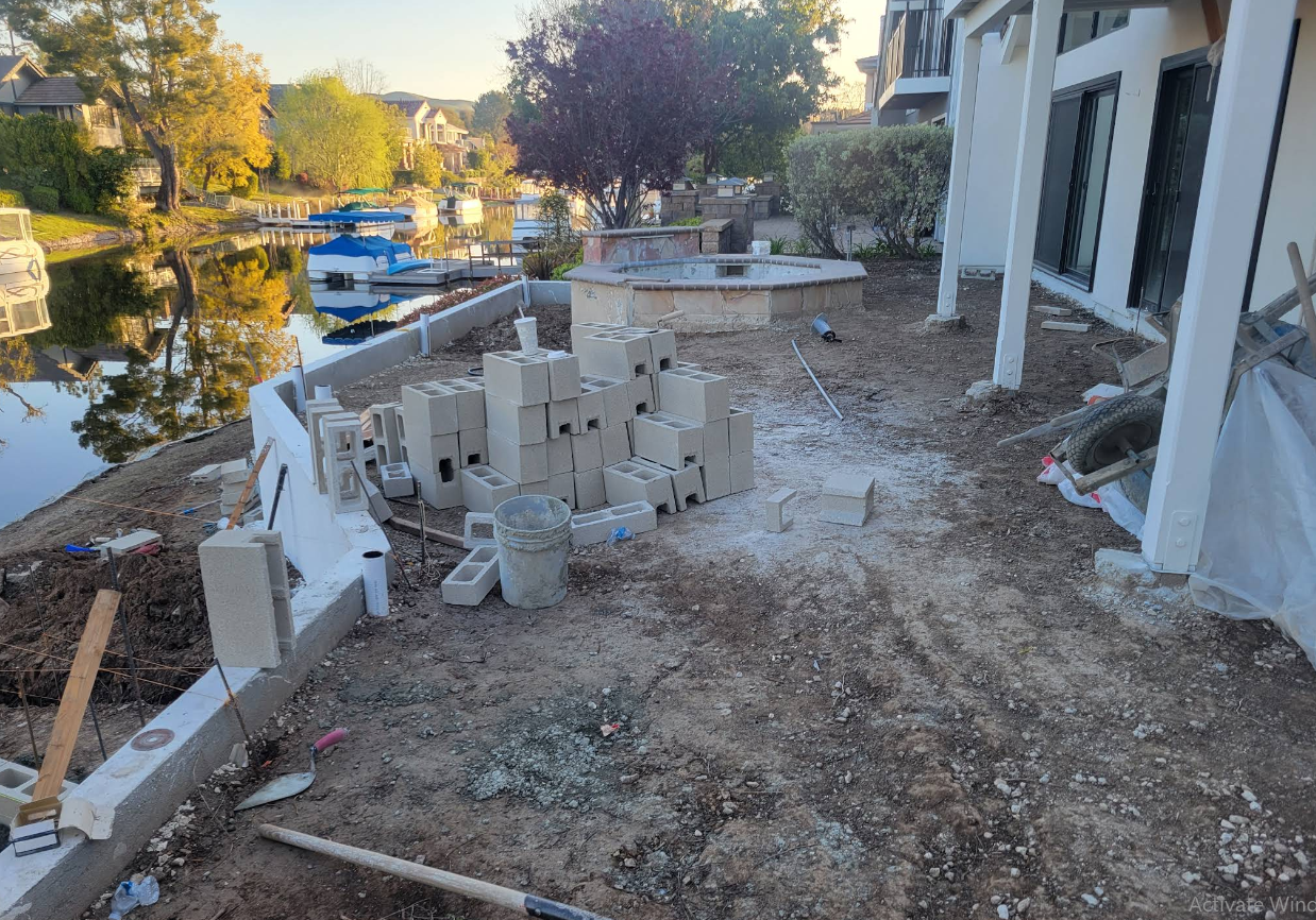 Damaged porch with debris and broken furniture beside a canal at sunset
