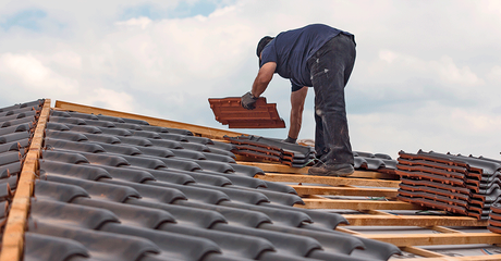 Worker placing roof tiles on a sloped roof during construction