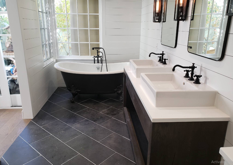 Modern bathroom with black freestanding tub, double sinks, and dark tiled floor