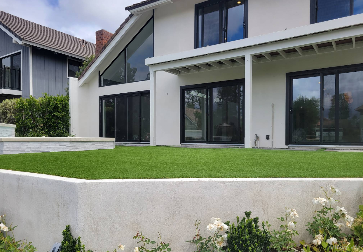 Modern white house with large windows, sloped roof, and a green lawn in front