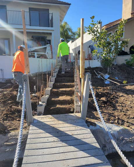 Workers install a stairway in a residential construction site between two houses.