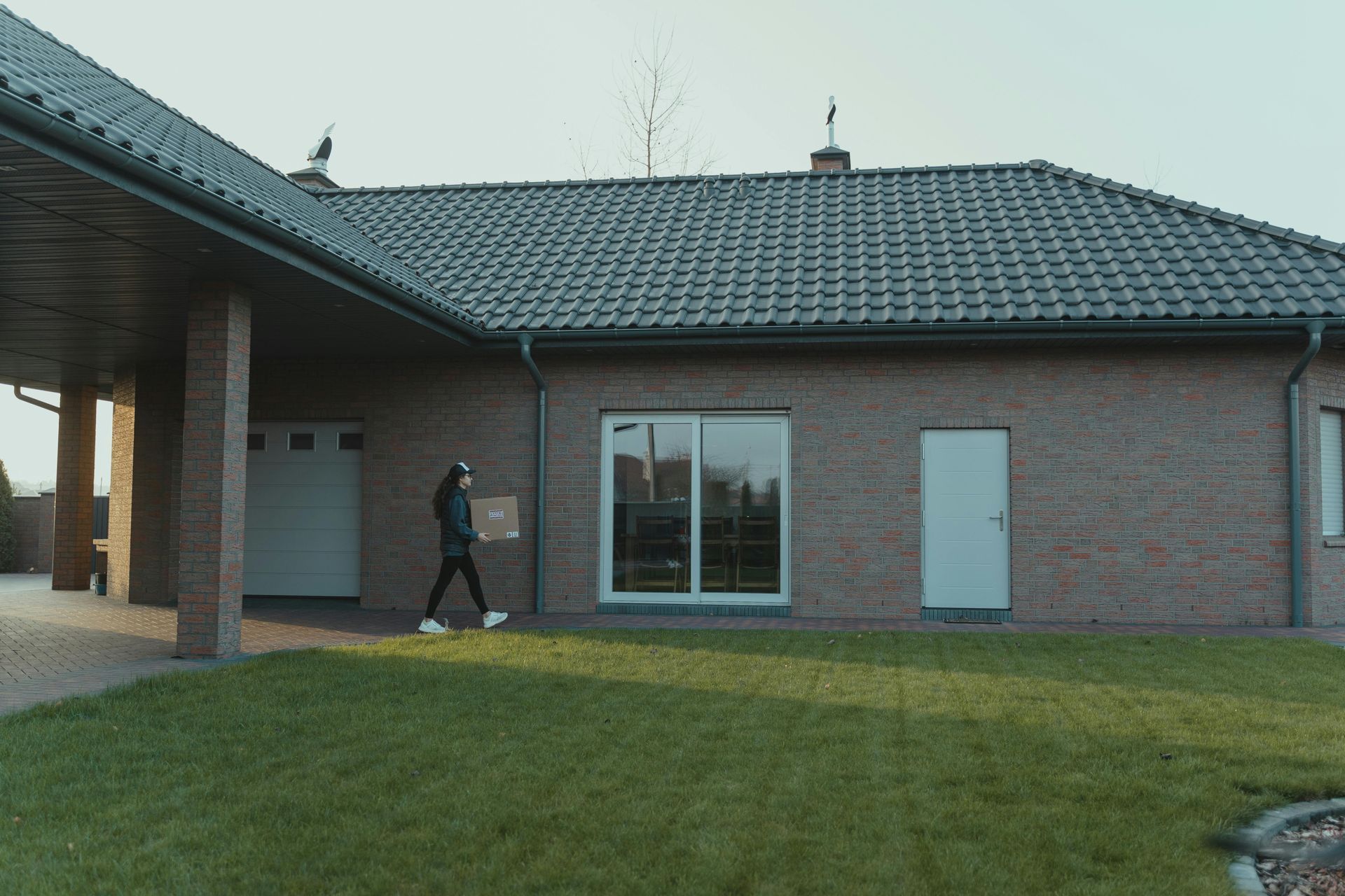 Brick house exterior with a person walking across the lawn toward the entrance