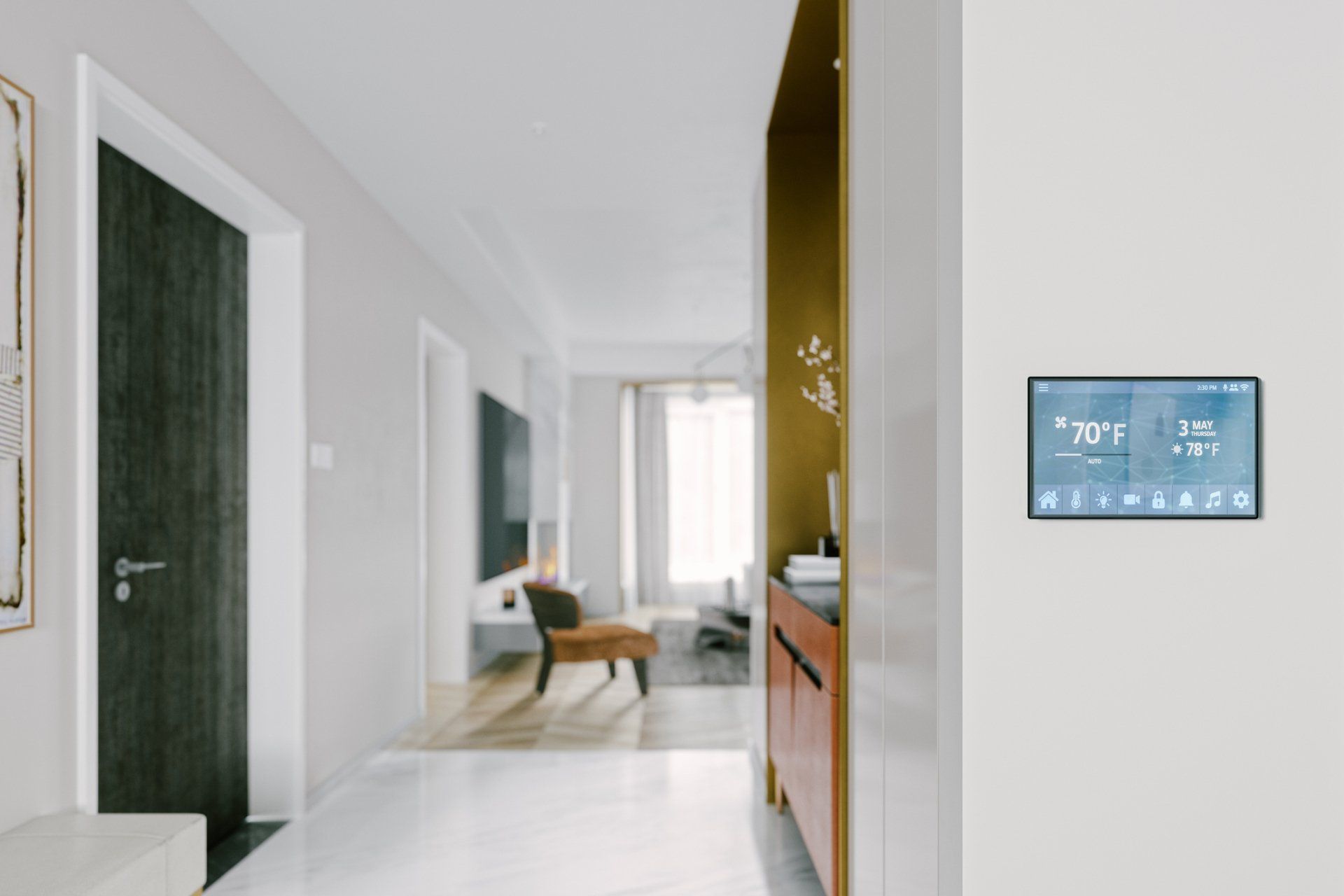 Hallway with digital thermostat, open doorway to living room. White walls, wood floor, modern decor.