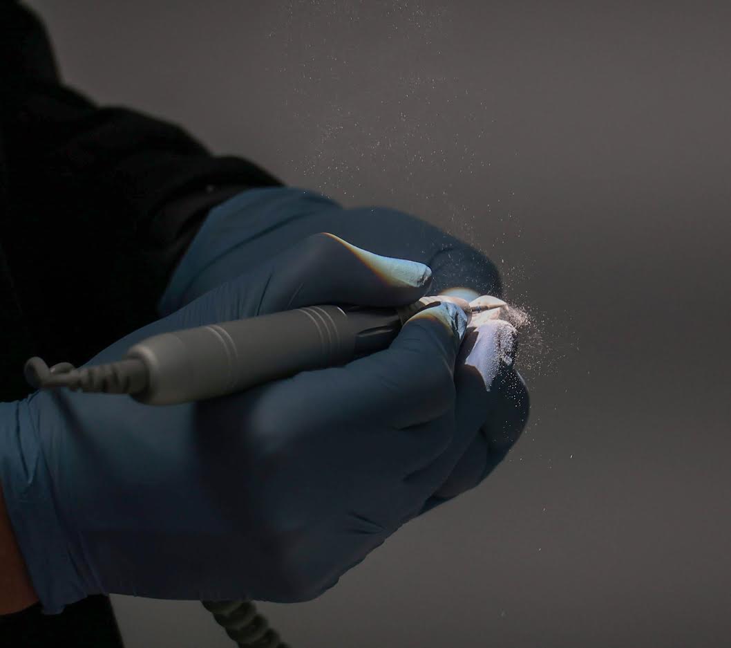 A person wearing blue gloves is holding a tool in their hand.
