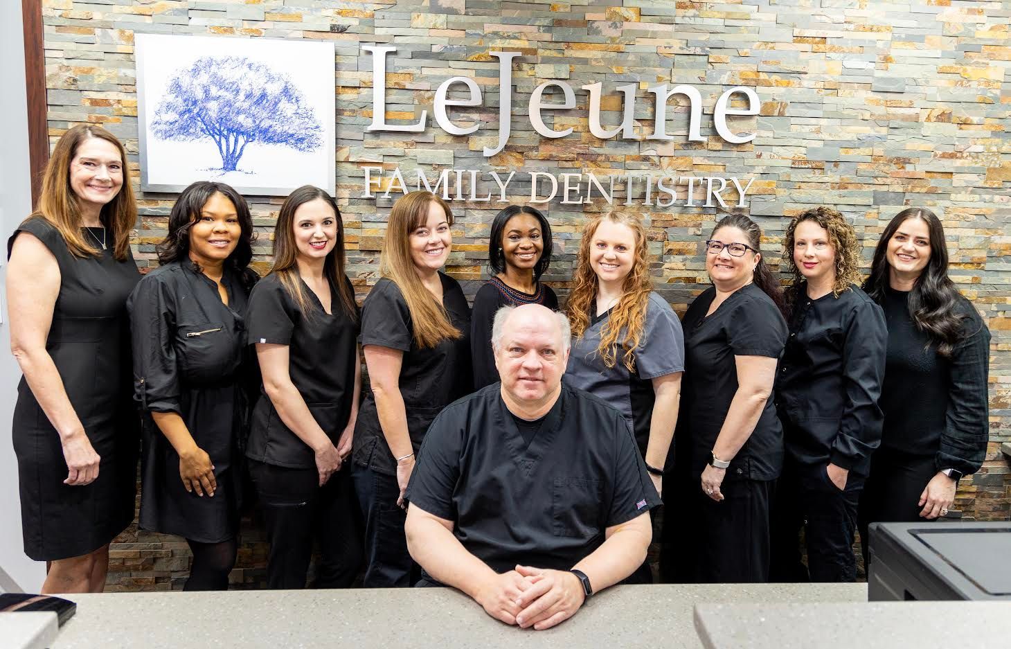 A group of people are posing for a picture in a dental office.