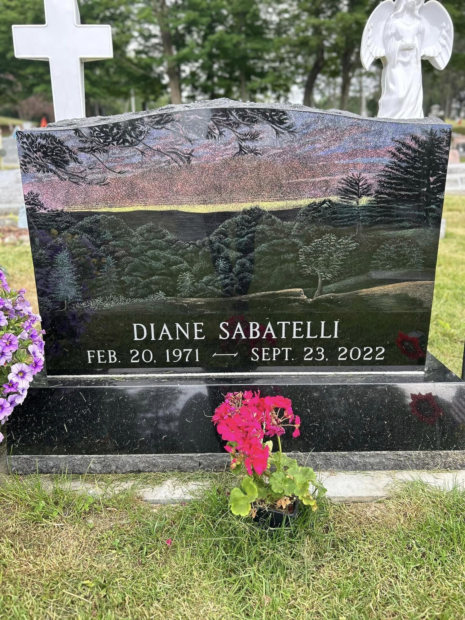 Black headstone with painted sunset scene,