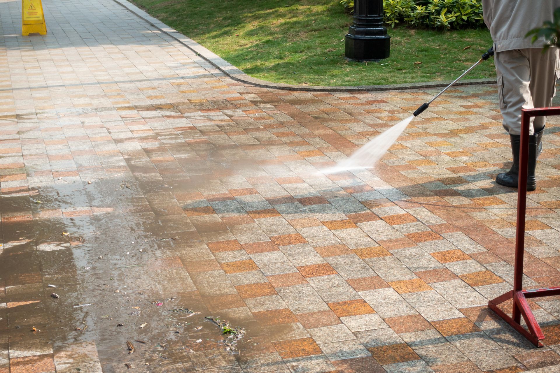 Person Pressure-washes a Brick Walkway Beside a Lawn — A1 Roof Cleaning In Hervey Bay, QLD
