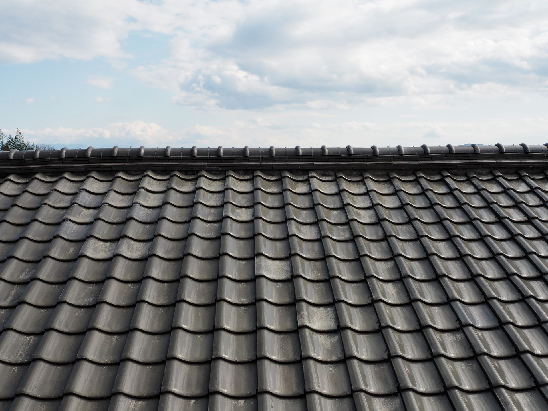 Dark Gray Tiled Roof With a Cloudy Sky Above — A1 Roof Cleaning In Hervey Bay, QLD