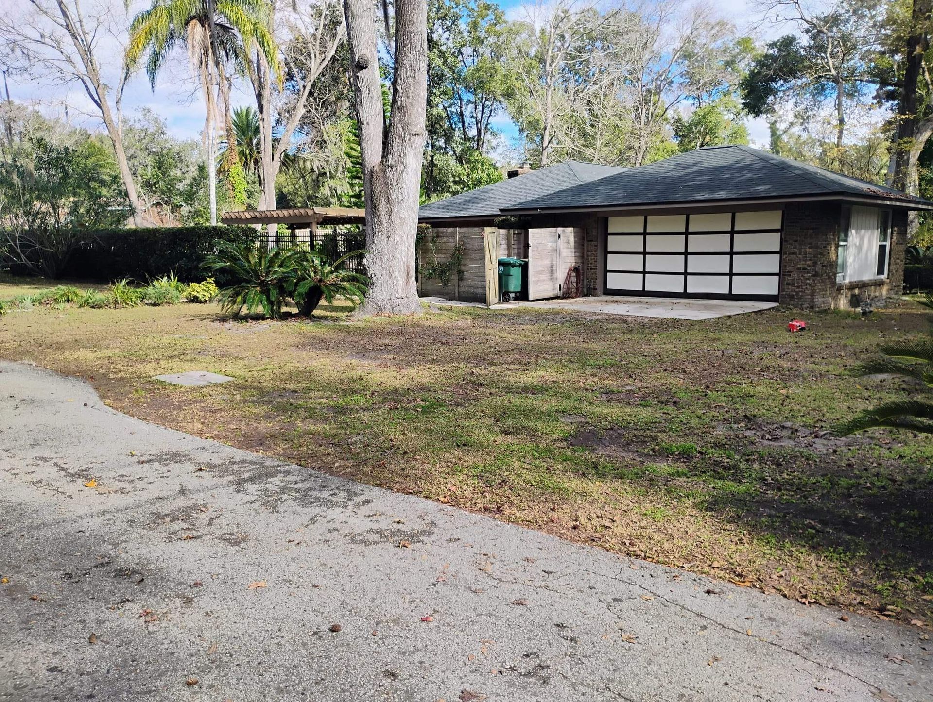 A one-story brick house with a dark roof and a driveway in a yard.