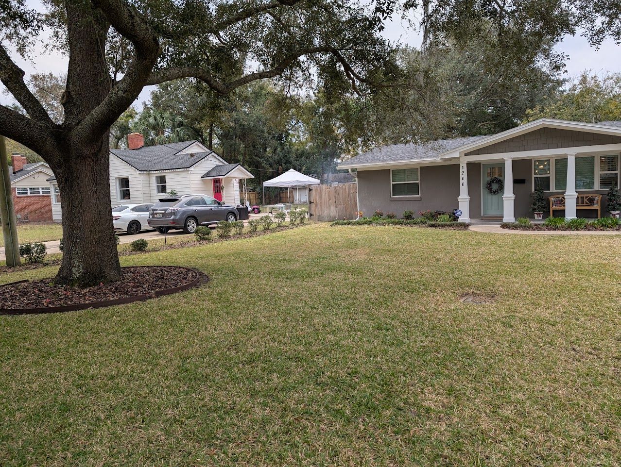 Houses and yard: a tan house on the right, a white house on the left, separated by a fence and a well-maintained lawn.