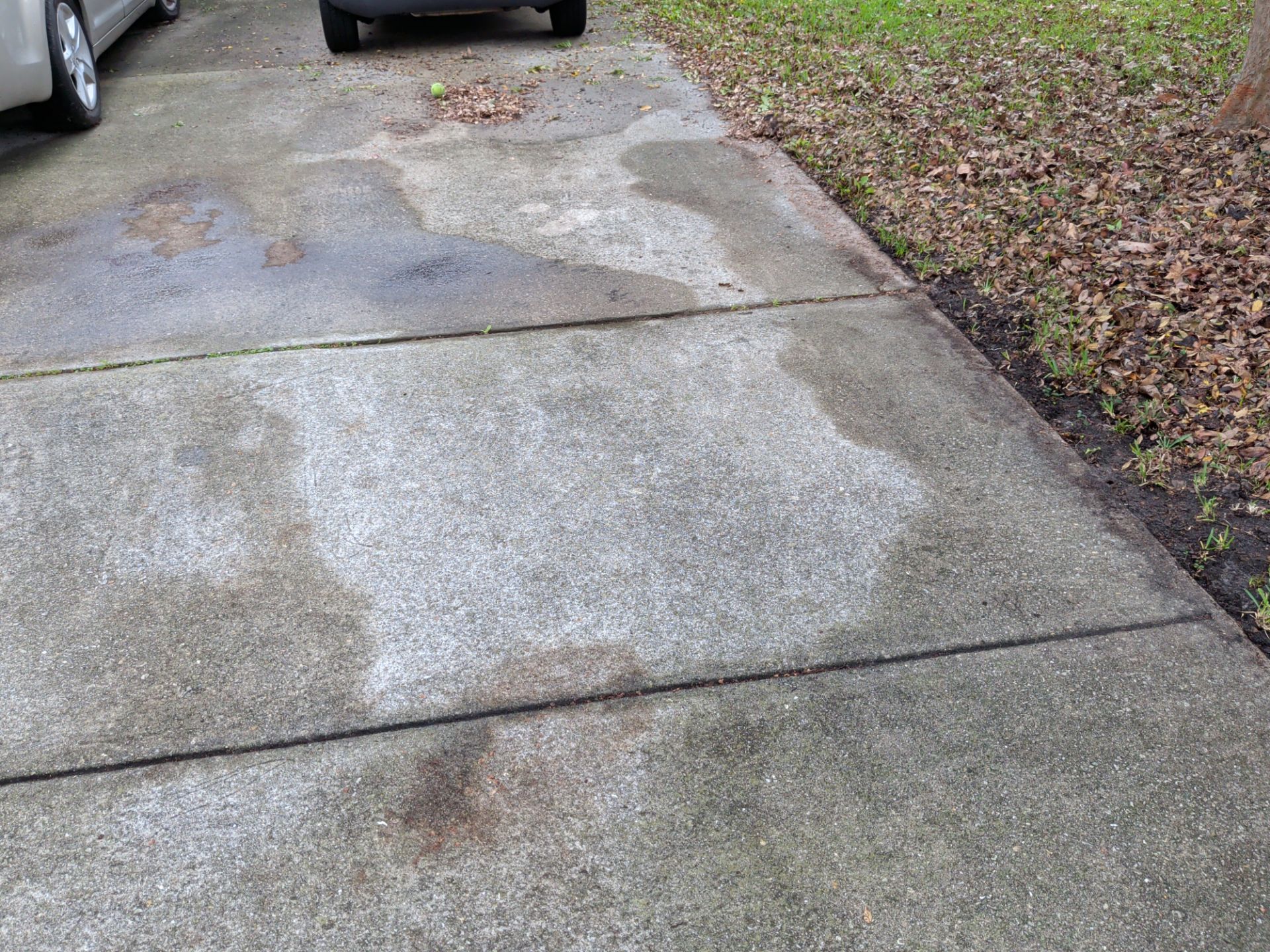 Driveway made of concrete pavers with stains and puddles.