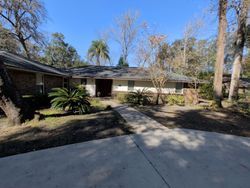 House exterior with a concrete driveway and surrounding trees under a blue sky.