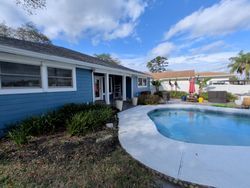 Blue house with pool, white trim, and sunny sky.