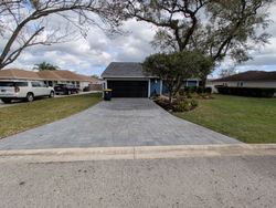 Blue house with dark garage door and a gray paver driveway.