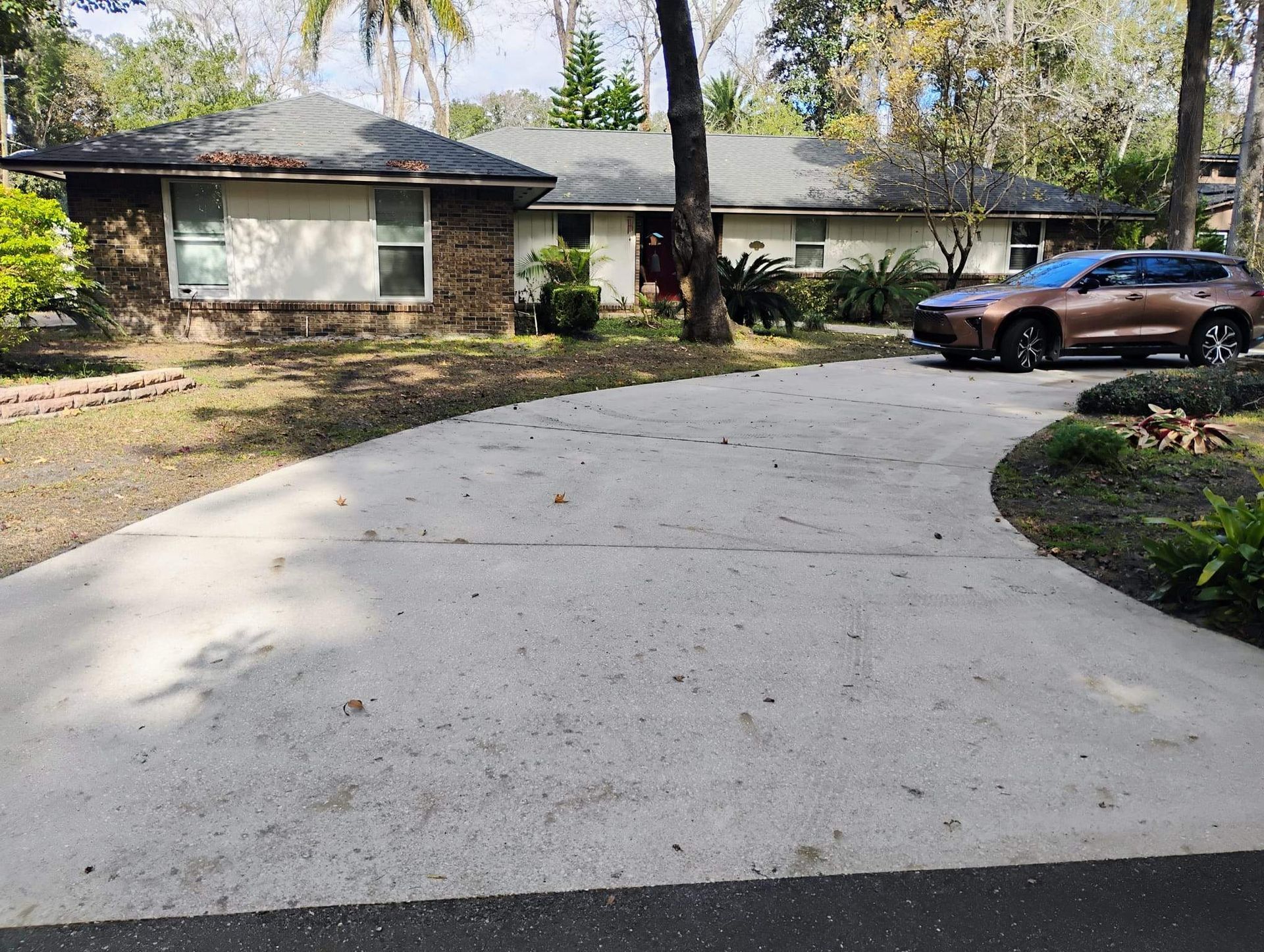 A single-story house with a long driveway and a brown SUV parked in front.