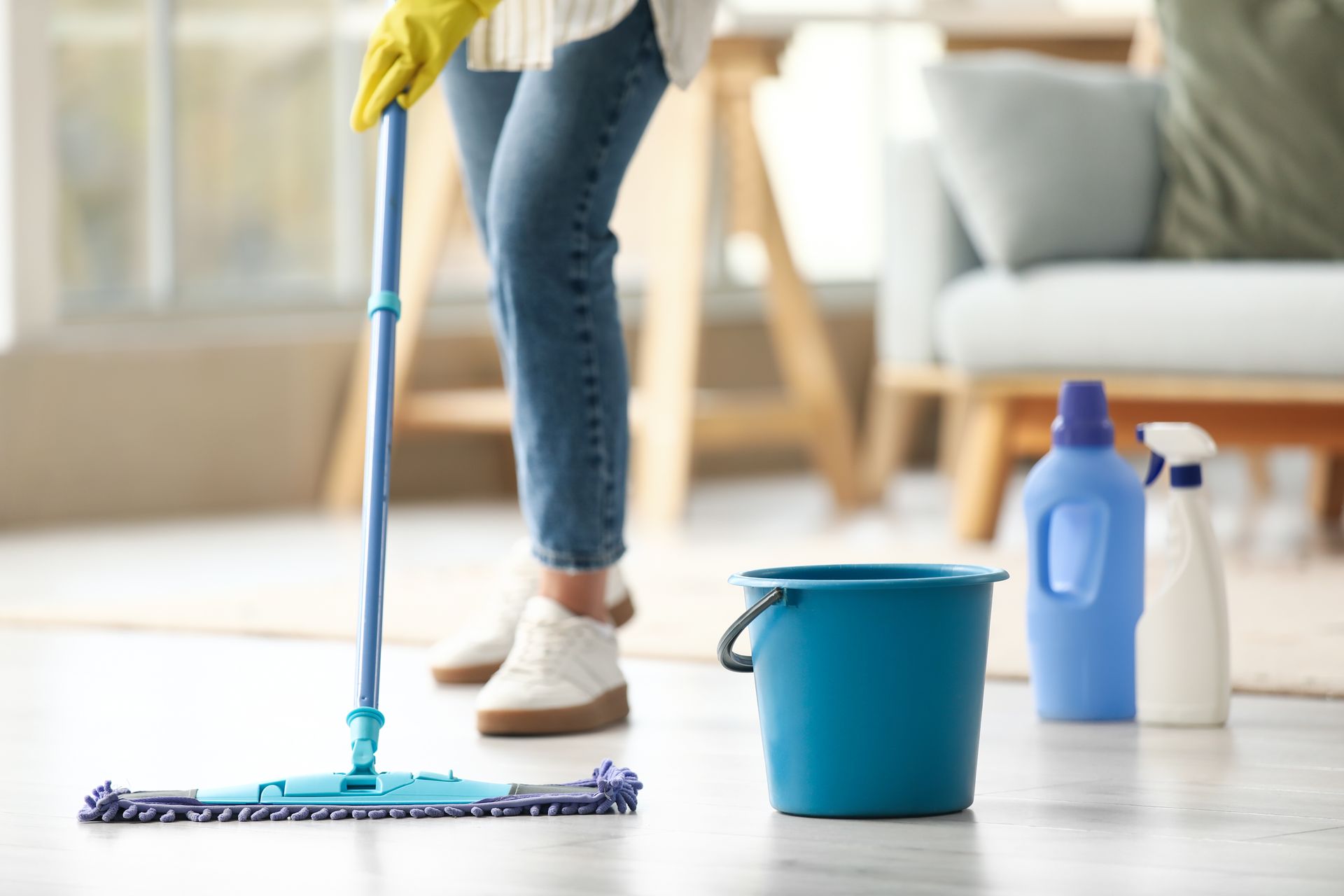 Cleaning crew mopping and vacuuming a bright living room with stairs and a couch