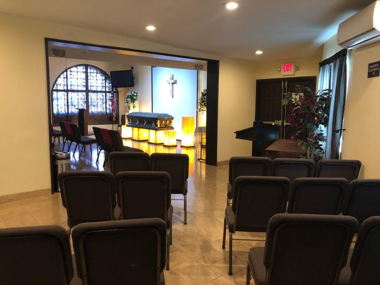 Church chapel with rows of chairs facing a lit altar and arched stained-glass windows