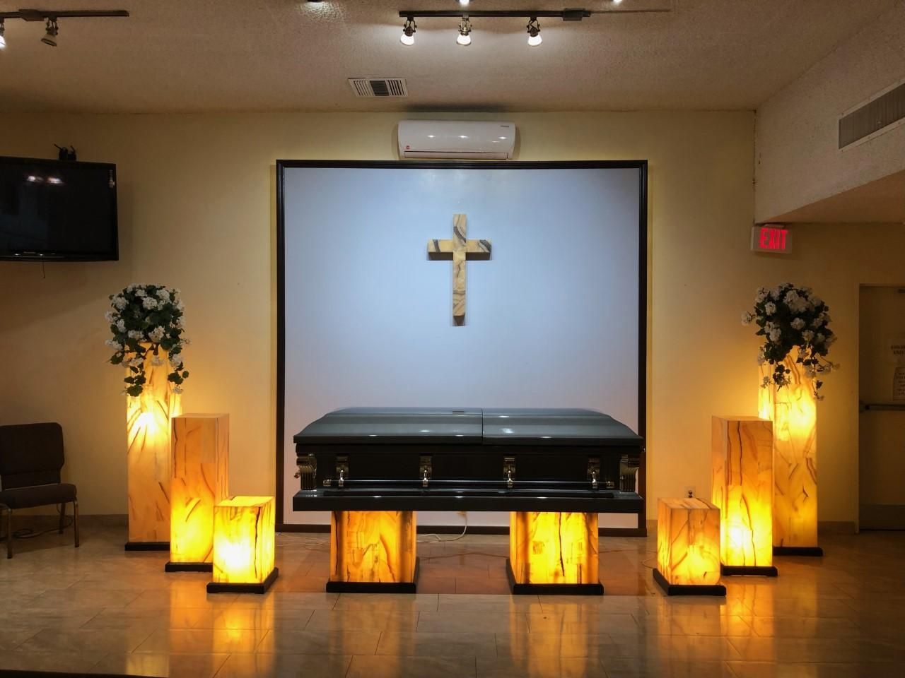 Church altar with a cross, casket, and glowing lanterns in a dimly lit room